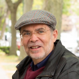 Headshot of David Mitch wearing a flat cap and a leather jacket.