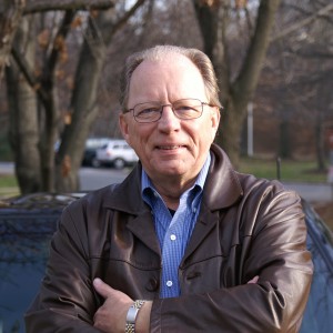 Photo of Donald F. Norris wearing a brown leather jacket, sitting at the hood of his car.